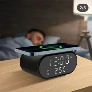 Bežični punjač sa LED satom i termometrom, postavljen na noćnom stočiću uz prikaz bežičnog punjenja telefona.