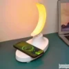 LED lampa u obliku Meseca sa RGB osvetljenjem, Bluetooth zvučnikom i integrisanim bežičnim punjačem na drvenom postolju.